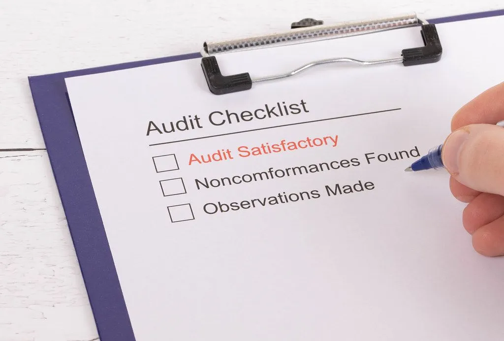 Medical billing audit checklist on a clipboard with options for Audit Satisfactory, Nonconformances Found, and Observations Made.