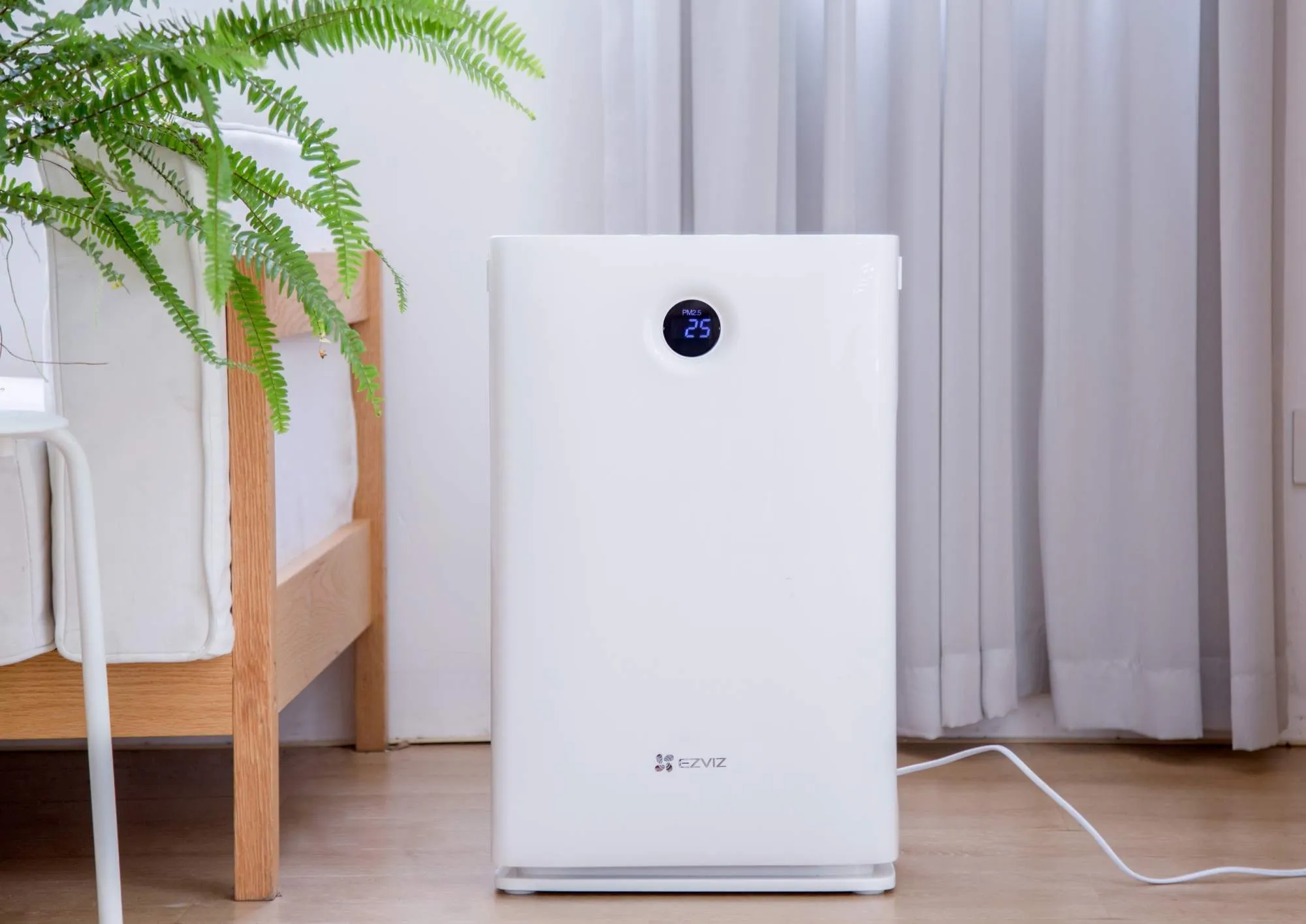 UV air purifier placed in a bright room near a bed and a green plant, highlighting concerns about UV air purifier side effects.