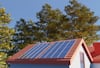 Residential rooftop with solar panels installed on a modern home surrounded by trees under a clear blue sky in Minnesota or Wisconsin